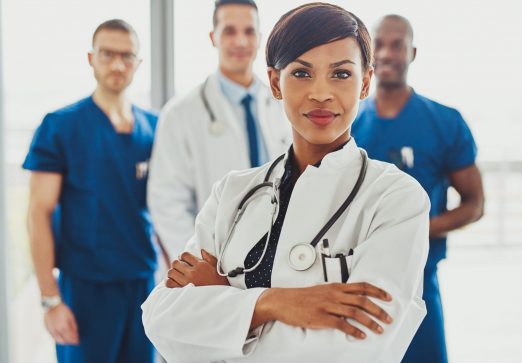 Black female doctor in front of team Black female doctor in front of team, looking at camera with medical team in background